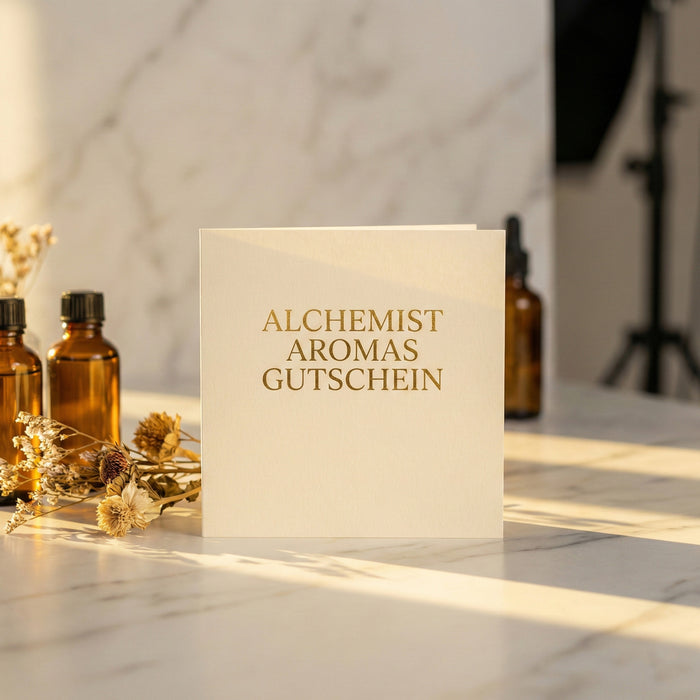 Alchemist perfume gift voucher displayed on a marble surface with floral accents